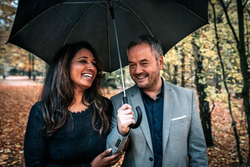 Smiling couple in autumn under umbrella