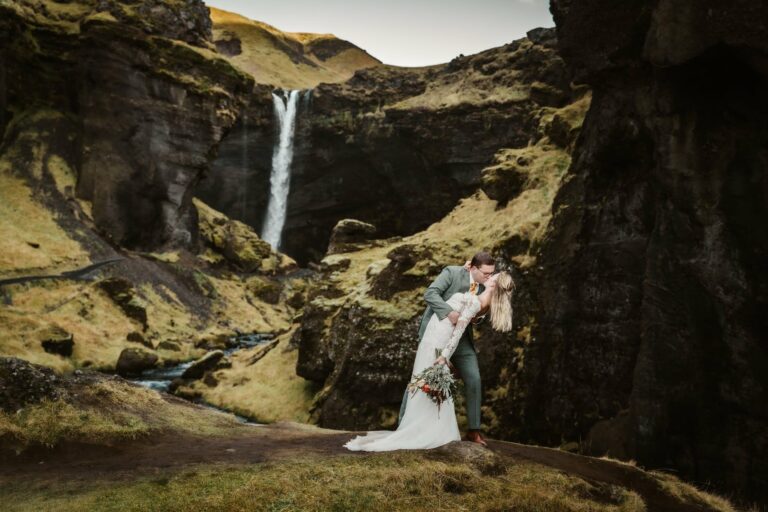 Groom dipping his bride at the gorge of Kvernufoss during their elopement
